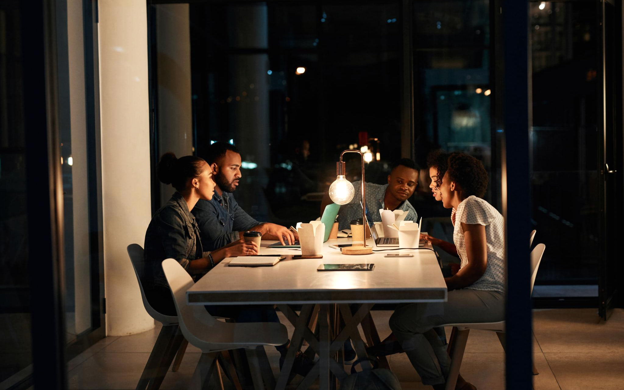 A service-business team reviewing work together in an office at night.